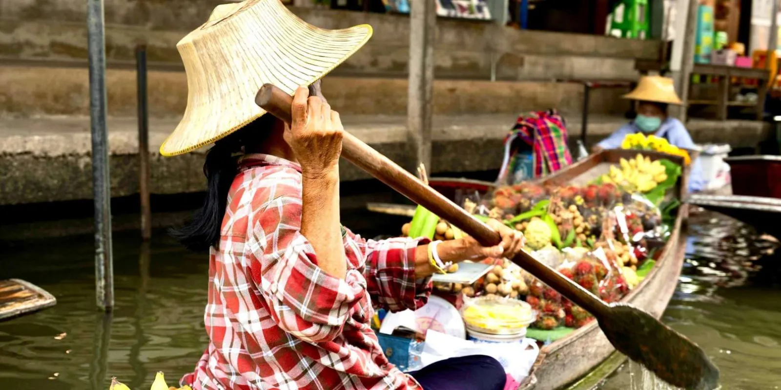 Fruit seller paddling a wooden boat