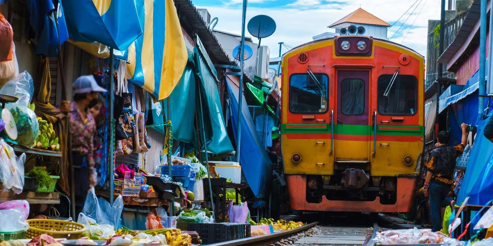 Train approaching beside blue market awnings